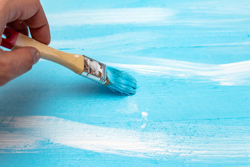 Painting with the paint brush blue color paint on the wooden DIY background for photo