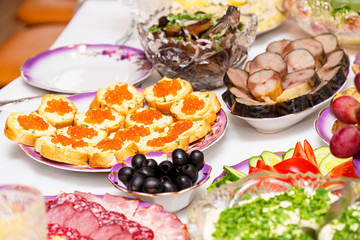Served table. Snacks, fruits, sandwiches, salads, caviar and slicing on the holiday table. Selective focus