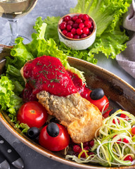 Baked sturgeon fish with tomatoes and red sauce served with wine. Closeup
