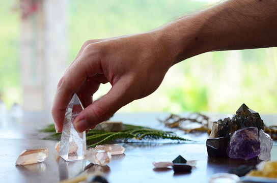 Beautiful Clear Quartz, variety of crystal on wood table. Bright Quartz crystal, healing crystal being held in hand. Woman holding quartz tower, crisp colors in natural lighting. Vibrant meditation.