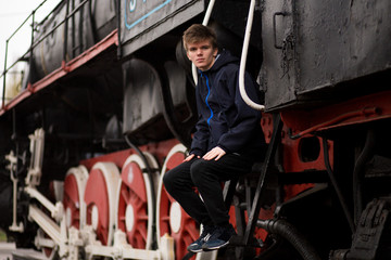 Fototapeta na wymiar Portrait of man student on platform of train station near old train