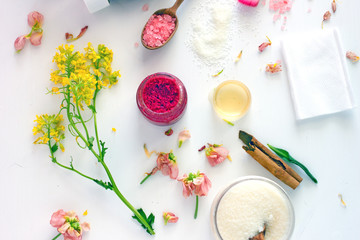 Top view of a bottle of essential oil next to the twigs of plants and fresh flowers, cinnamon,...