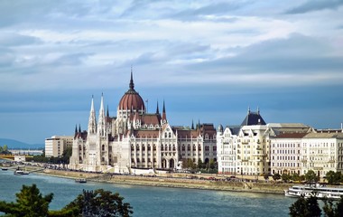 Water view of Hungarian Parliament Building on a hazy blue sky day.