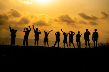 The silhouette of a group of people is celebrating success on the hilltop..