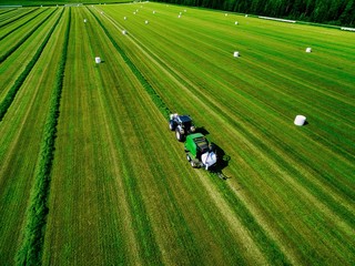 Aerial view of Tractor mowing green field in Finland.