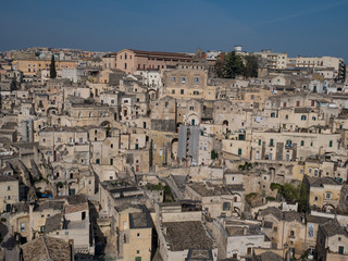 Fototapeta na wymiar Panoramic view of typical stone houses of Sassi di Matera and church under blue sky with clouds, capital of europe culture 2019. April, 2019