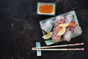 Top view of vietnamese vegetable spring rolls on a dark brown stone background, horizontal shot with copyspace