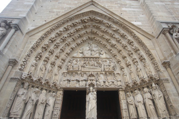 The Red Door of Gothic cathedral in West Portals Facade of Notre Dame, France, historic monuments detail ancient statue art outside of cathoric church, travel destination backgrounds