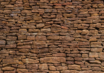 The wall is made of old, ancient stones, with plants growing from seams and cracks. close up.