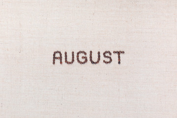 The word August written with coffee beans shot from above, aligned in the center.