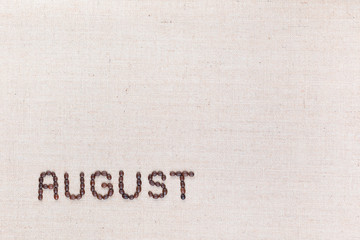 The word August written with coffee beans shot from above, aligned at the bottom left.