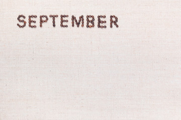 The word September written with coffee beans shot from above, aligned at the top left.