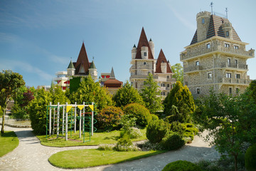 Fototapeta premium modern Victorian-style luxury hotel with a small children's play area at the foot, against a blue sky in clear sunny weather