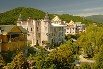 view from a height. modern luxury hotel in Victorian style with beautiful well-groomed trees against the backdrop of a mountain range and blue sky in clear sunny weather