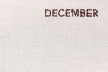 The word December written with coffee beans shot from above, aligned at the top right.