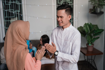 veiled woman and young man greet each other apologizing during the Eid holiday