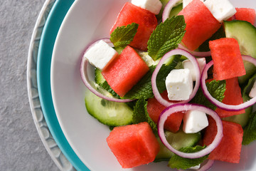 watermelon salad with feta cheese,mint,onion and cucumber on gray background.. Close up