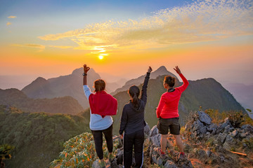 Three Asian Backpacker trekking acting over golden cloud 