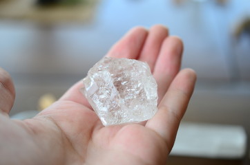 Woman's hand holding clear quartz! Beautiful translucent Quartz specimen, bright colors in natural lighting. Witch holding crystal, Wiccan crystal offerings. Shiny quartz stone being held.