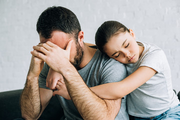 sad kid embracing stressed father in living room