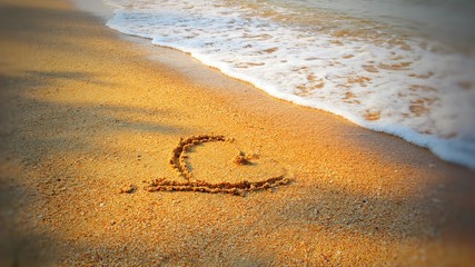  Heart shape on the sand by the sea, reflecting the morning sun