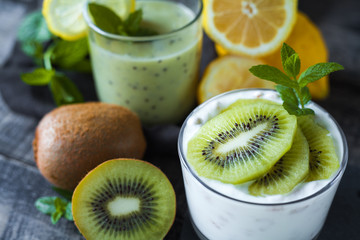 Fototapeta na wymiar Homemade proteic greek yogurt with kiwi, lemon and mint and healthy shack of kiwi, banana and lemon