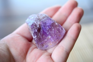 Raw Ametrine being held in woman's hand. Raw purple crystals, amethyst and citrine. Healing crystal, witches hand. Wiccan tools, spell casting. Deep purple reiki healing.