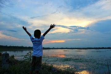  A happy little boy stood on the river side in the evening