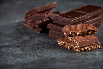 Chunks of broken chocolate stacked on black board.