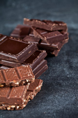 Chunks of broken chocolate stacked on black board.