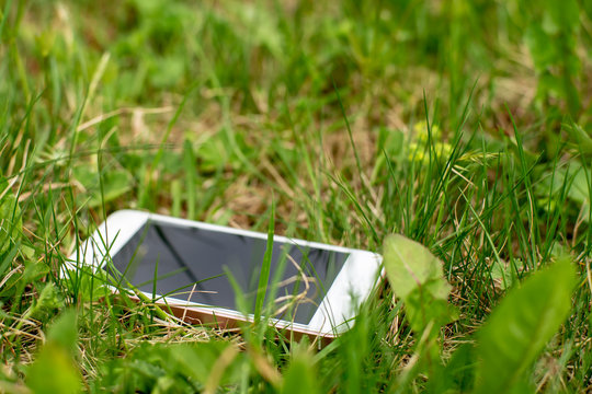 Lost Smartphone Lies In Green Grass On A Spring Day.