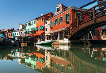 Colorful houses in Burano with reflection in canal, Venice, Italy