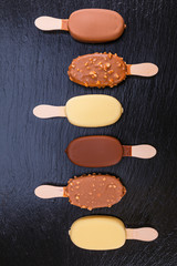Ice cream on stick covered with chocolate on black slate
