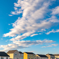 Square Row of houses under a vibrant blue sky with fluffy clouds on a sunny day