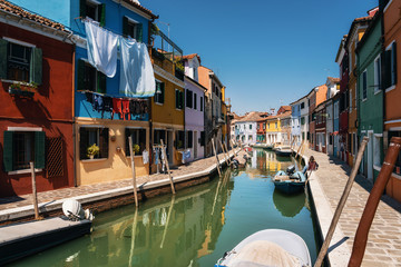Fototapeta na wymiar Laundry dries on the facades of colorful houses in Burano close to canal, Venice, Italy