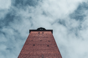 Looking up a brick tower on the sky with clouds