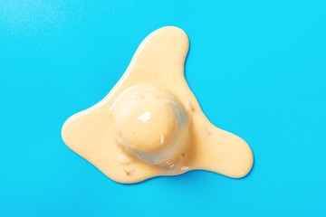 top view mango flavor ice cream ball in a melting process on blue background