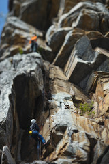 Climber climbs up the rope against the backdrop of overhanging rocks. Tilt-Shift effect.