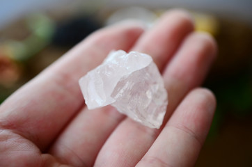 Woman's hand holding clear quartz! Beautiful translucent Quartz specimen, bright colors in natural lighting. Witch holding crystal, Wiccan crystal offerings. Shiny quartz stone being held.