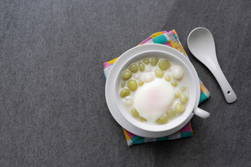 Pandan Thai glutinous rice balls (Bua Loi) in white bowl on table,Boiled egg.