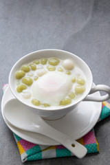 Pandan Thai glutinous rice balls (Bua Loi) in white bowl on table,Boiled egg.