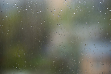 Rain drops running down dirty glass window pane. Summer time