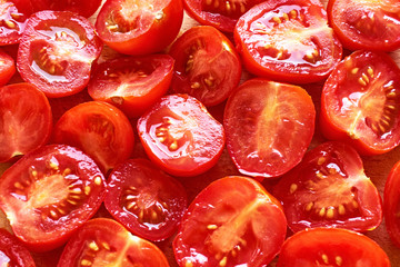 Freshly cut juicy red cherry tomatoes on a cutting board in backlight for use as a culinair...