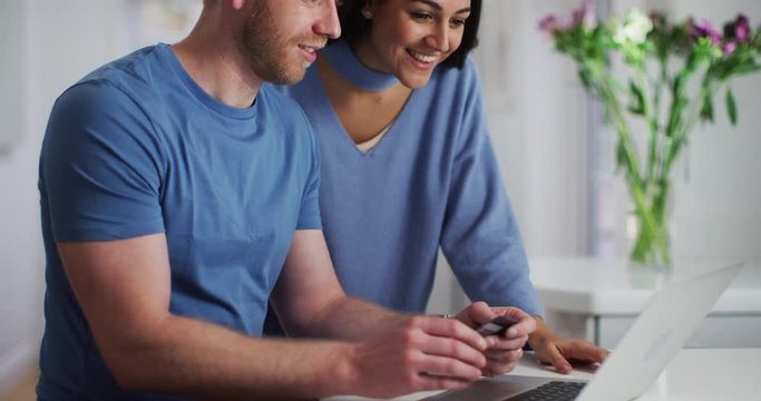 4K Excited couple winning an online auction & making payment with credit card. Slow motion.