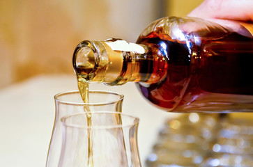 Obraz na płótnie Canvas Cognac pouring from bottle into glass . Alcoholic, beverage.