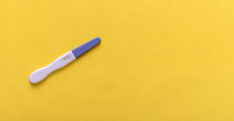 Pregnancy test on yellow background.