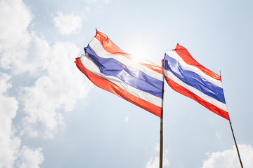 Flags of Thailand on the wind with bright sun on the background
