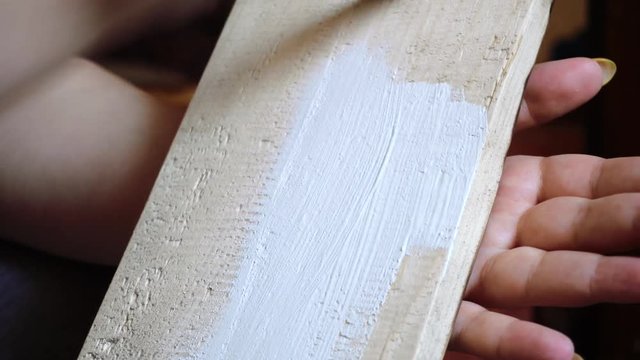 painting a wooden board with a white paint brush close-up
