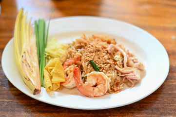 Pad thai , Thai style noodle with shrimps on white dish and wooden table