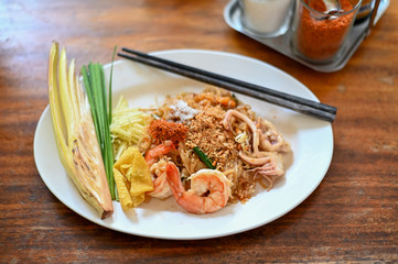 Pad thai , Thai style noodle with shrimps on white dish and wooden table